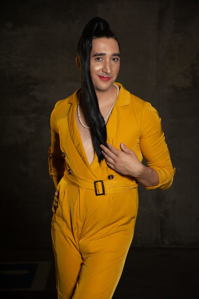 Person with a long dark ponytail and yellow jumpsuit